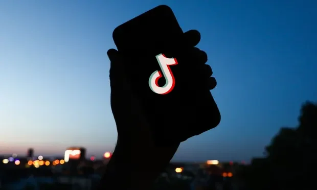 a hand holding a cell phone with a logo on it
